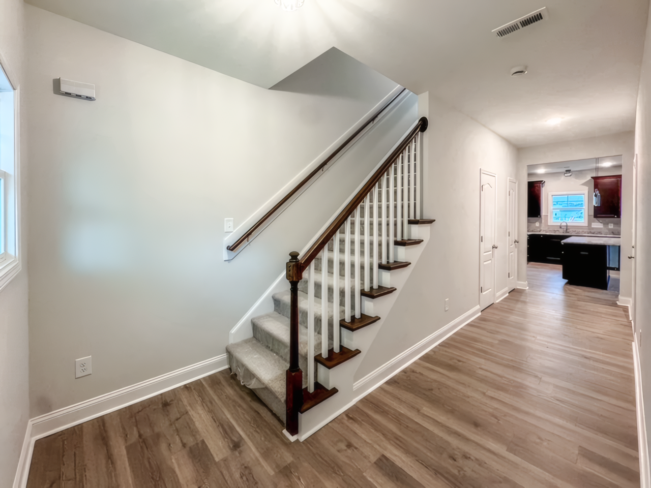 View of inside house. You can see a white staircase with wood handle and steps