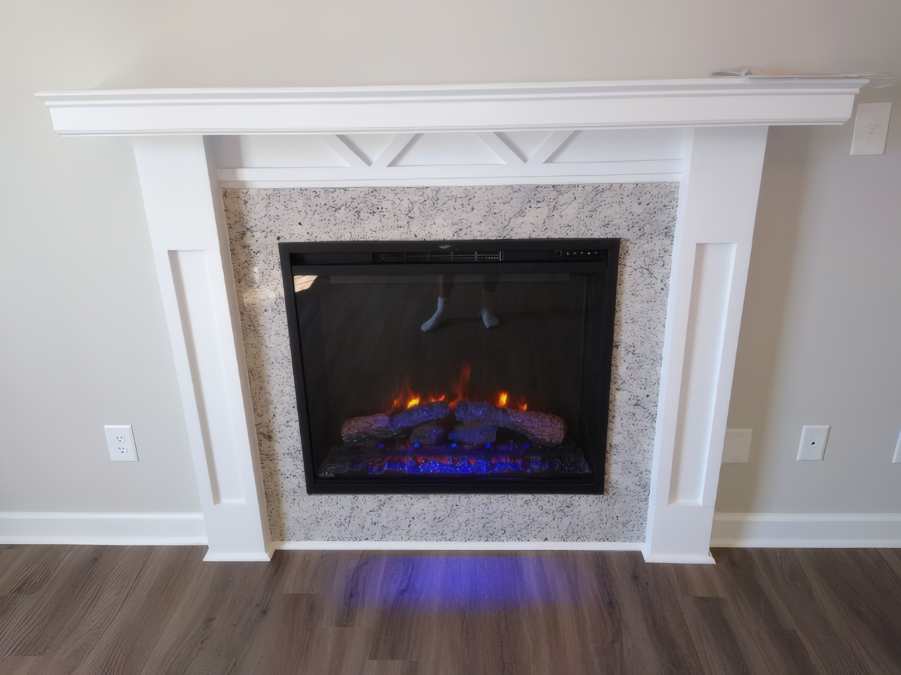 Build-in white colored fireplace, it is on and has a small flame