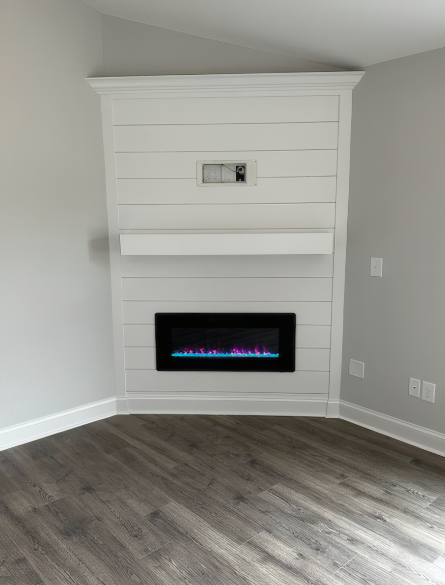 Large build-in fireplace that has a small flame, also has a small mantle above the fire section